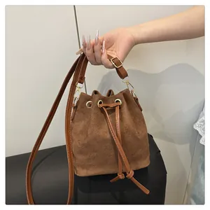 Detail of brown suede bucket bag with gold metal eyelets and drawstring closure