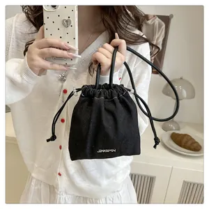 Detailed shot of black mini bucket bag with drawstring closure and silver metal logo