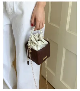 Detail der dunkelbraunen Mini-Tasche mit Perlengriff und eleganter Metallkette