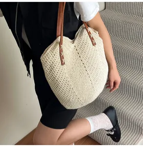 Detailed texture of the crochet woven pattern and brown leather straps on the straw tote bag