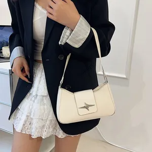 Détail d'un sac porté épaule ivoire avec une boucle en étoile sur cuir mat élégant
