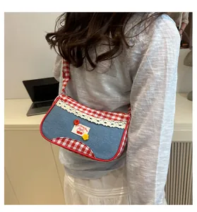 Detail of denim and red gingham shoulder bag with lace trim and cherry patch