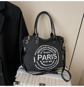 Detail of black canvas tote bag with white vintage print and adjustable strap for travel
