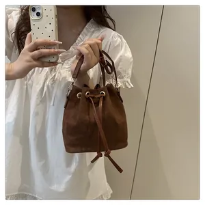 Detail of dark brown matte bucket bag showing drawstring closure and gold hardware