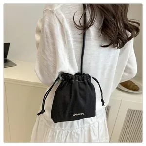 Detailed view of a mini black bucket bag with silver logo in a casual lifestyle setting