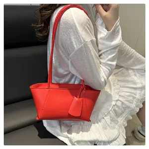 Detail of red PU leather shoulder bag featuring minimalist tote design on a white dress