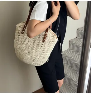 Close-up of beige woven tote bag texture with brown leather straps and cross stitching