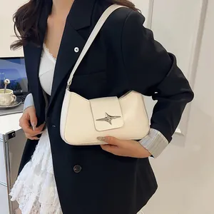 Vue latérale du sac à bandoulière crème avec boucle étoile sur un blazer noir chic