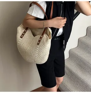 Close-up of woven beach tote bag featuring brown leather straps and detailed stitching
