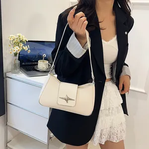 Sac bandoulière en similicuir blanc avec boucle étoile argentée porté avec une veste noire
