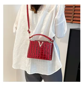 Detail of red crocodile texture handbag with silver V-shaped buckle and leather strap
