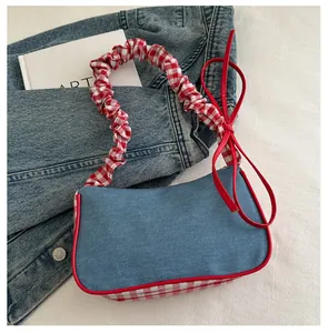 Detail of denim underarm bag with red gingham ruffled handle and bow tie accents