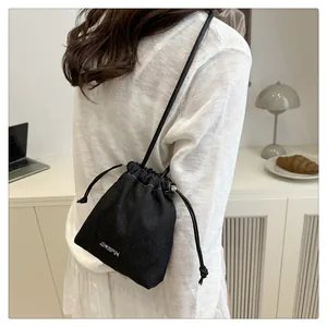Detailed view of the black drawstring bucket bag with silver JINGPIN metal plaque logo