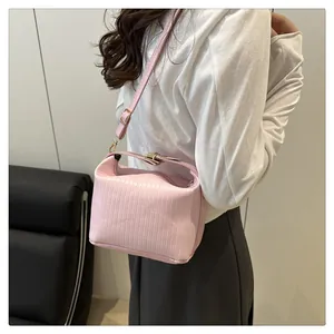 Détail de la texture rayée du sac à main rose avec des finitions en métal doré