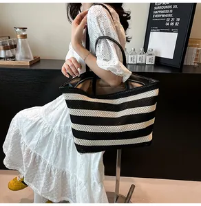 Detalle del bolso tote tejido a rayas blancas y negras con asas de cuero de primera calidad