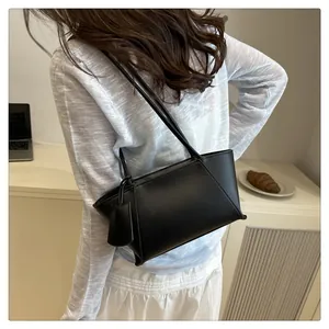 Detail of a black leather tote bag showing side stitch accents and branding tag