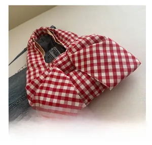 Close-up of red and white gingham fabric tote bag with soft pleated side and brown lining
