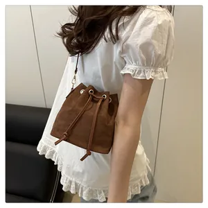 Close-up of brown suede mini bucket bag with drawstring closure and gold eyelet details