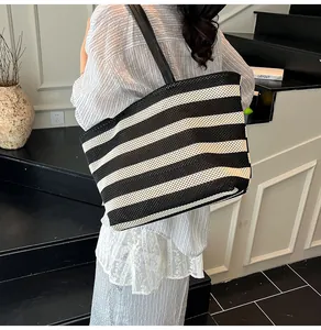 Detalle de bolso tote de malla a rayas blancas y negras con correas de cuero en modelo