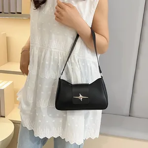 Détail d'un sac d'épaule noir avec étoile argentée porté par un mannequin élégant