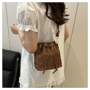Close-up of a brown matte bucket bag with drawstring closure and golden metal eyelets