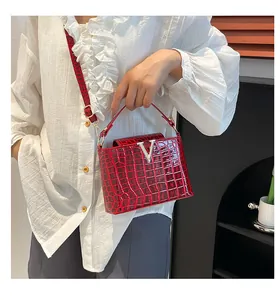 Detail of red crocodile texture handbag featuring V-logo and printed wide strap