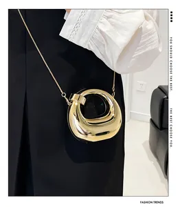 Primer plano de mini bolso dorado efecto espejo con fina correa de cadena metálica