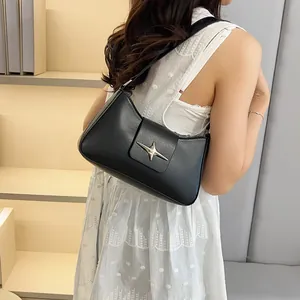 Sac bandoulière noir avec boucle étoile argentée porté avec une robe en dentelle