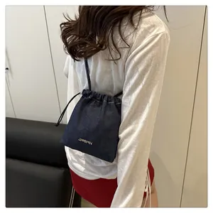 Detailed back view of a navy denim drawstring bucket bag with silver brand logo
