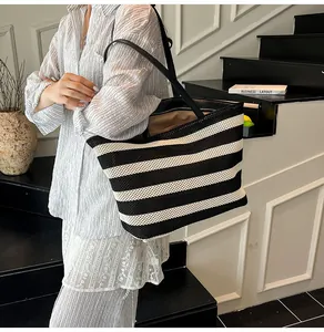 Detalle del bolso tote tejido a rayas blancas y negras con asas de cuero y gran capacidad