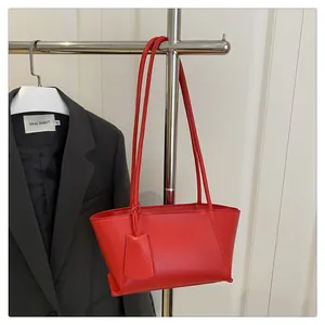 Detail view of a red leather shoulder bag hanging on a rack with sleek shoulder straps