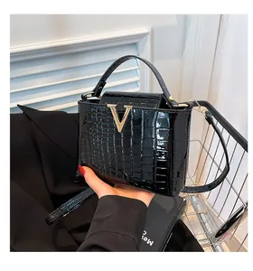 Close-up of black croc-embossed patent leather bag with gold V-shaped metal logo