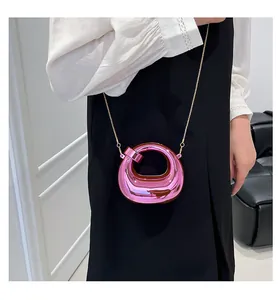 Macro detail of glossy pink metallic crescent bag with elegant gold chain strap