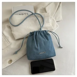 Mini blue denim bucket bag with silver JINGPIN logo compared to a mobile phone size
