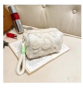 Detail view of plush white clutch bag with embossed heart patterns and green accents