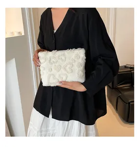 Detail van witte pluche make-uptas met hartpatroon in reliëf en zachte faux fur textuur