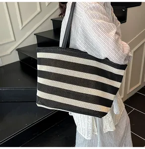 Bolso tote de tejido a rayas blancas y negras con correas de cuero llevado por una modelo