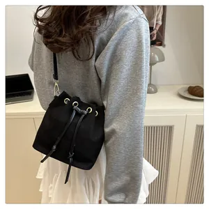 Detail of black drawstring bucket bag featuring gold metal rings and leather shoulder strap
