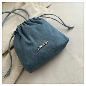 Close-up of blue denim bucket bag featuring drawstring closure and metal JINGPIN logo