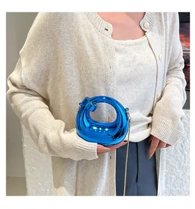 Detalle de bolso de media luna azul metalizado con cadena dorada en una modelo