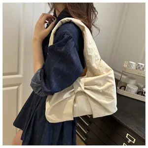 Detail of a beige bow-knot hobo bag with crinkled texture fabric on a model's shoulder