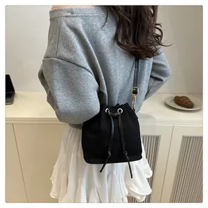 Minimalist black canvas bucket bag with drawstring closure and golden hardware