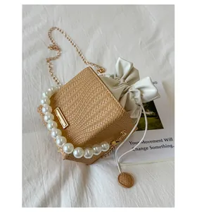 Detailed top view of a woven bucket bag with pearl handle and golden chain strap