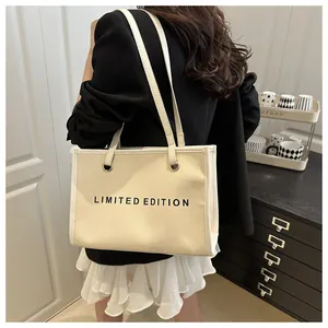 Detail of beige canvas tote bag with black Limited Edition print and gold metal rings