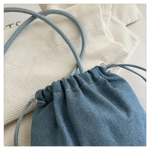 Detail of light blue denim bucket bag showing drawstring closure and texture