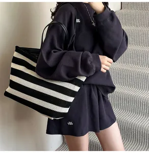 Detalle de bolso tote tejido a rayas con conjunto de descanso morado en punto gofrado
