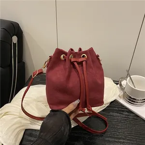 Classic burgundy suede drawstring bucket bag with gold hardware and leather shoulder strap