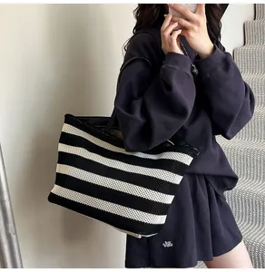 Detalle del bolso tote tejido a rayas negras y blancas con textura fina y correa de hombro