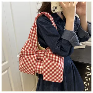 Detail of red gingham shoulder bag featuring a large bow and lightweight cotton fabric