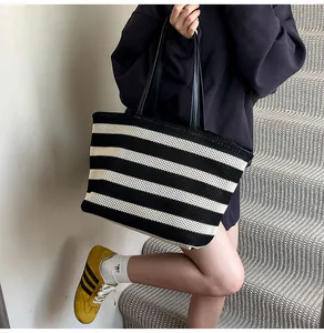 Detalle del bolso tote de punto a rayas con asas de cuero negro y textura de alta calidad